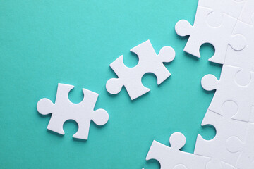 Obraz premium White jigsaw puzzle pieces on mint green background.