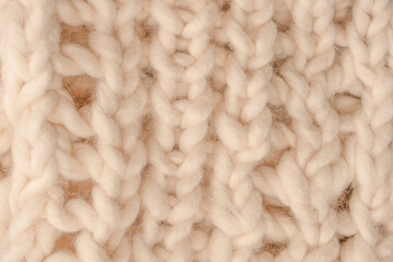 A fragment of beige knitted fabric, knitted from white sheep wool.