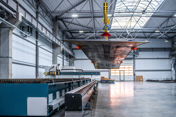 A large industrial building with a crane lifting a large piece of metal