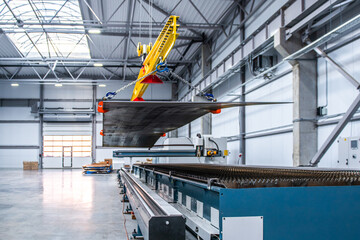 A large industrial building with a crane lifting a large sheet of metal