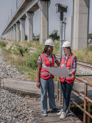 Multi-ethnic female engineers are consulting while inspecting the operation of the railway station using blueprints with Wookiee Tokki 