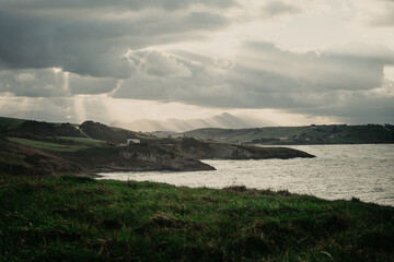 Pradera verde con montañas y cielo nublado en el norte de España.