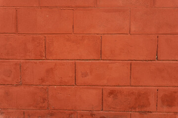 Muro de ladrillos rojos con textura rústica y líneas simétricas.