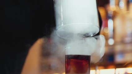 Focusing cropped hand bartender serving mist smoky Old fashioned in whiskey cocktail presentation for recommending special welcome tasty creative advertisement drink at beverage counter bar. Vinosity.