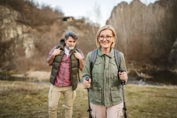 Fototapeta premium mature woman hiker backpacker explore forest with hiking sticks