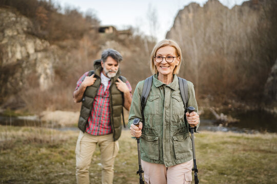 mature woman hiker backpacker explore forest with hiking sticks