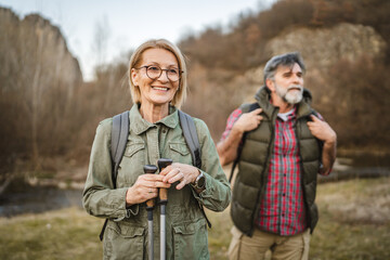 mature woman hiker backpacker explore forest with hiking sticks
