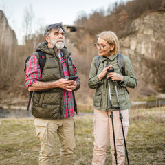 aged couple hiker backpacker explore forest and use mobile phone