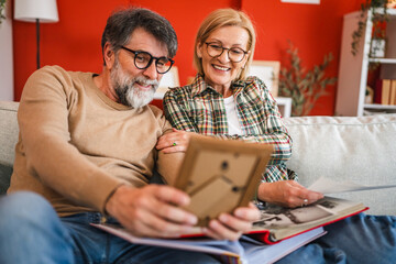husband and wife stand and watch family photo album in the living room