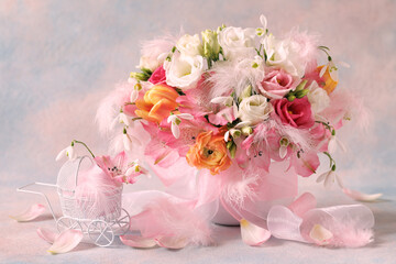 Pink and white bouquet of spring flowers with ribbon bow and decorative baby carriage on colorful background. Delicate greeting card in honor of newborn baby girl