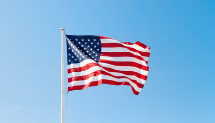Fototapeta premium USA flag waving against clear blue sky, symbol of freedom