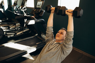 The athlete sits on a bench and slowly lifts the dumbbells up, concentrating on the correct...