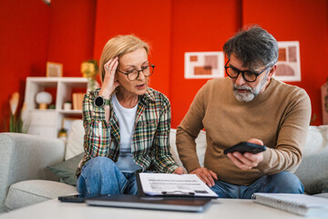unhappy mature couple use cellphone for contactless payment bills