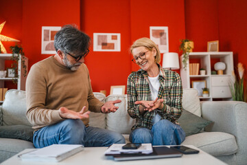 happy mature couple talk about bills, payment and home budget at home