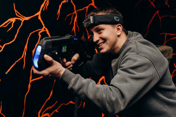 A young man in tactical clothing holds a laser blaster and takes aim. He wears a special headband with sensors that detect hits.