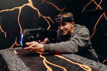 A player with a laser blaster peers into the darkness, looking for opponents. He has a headband...