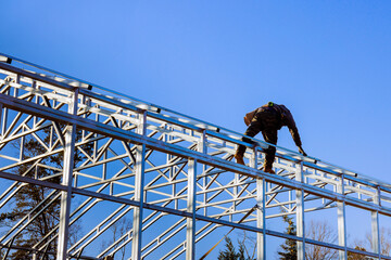 Naklejka premium Construction worker is assembling steel structure in warehouse building.