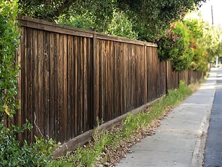Weathered wooden fence along residential sidewalk.