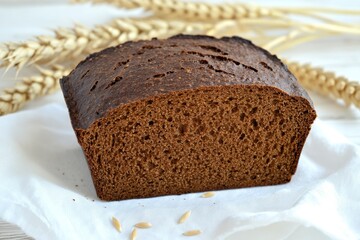 Freshly Baked Rye Bread Loaf with Wheat Stalks on White Cloth