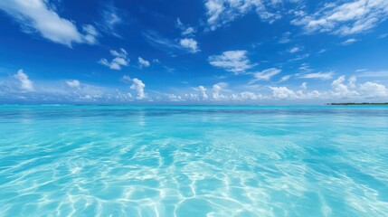 Fototapeta premium The clear blue ocean extends beneath a bright partly cloudy sky