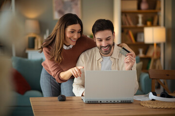 Couple using laptope to buy online. Man holding credit card to pay bills online