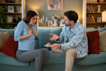 Young couple arguing about credit card bills and expenses, wife complaining about her husband's...