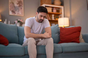 Obraz premium Sad man sitting on sofa in living room