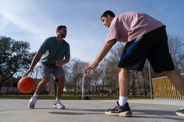 Caucasian and latin friends playing basketball on a sunny day