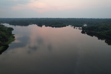 Obraz premium Majestic riverside view at twilight near lush green jungle