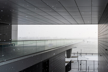 Modern exterior of the building. A observation deck for walking  against the background of a river in a snowfall in the arch of the building.