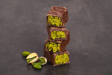Dubai chocolate. Chocolate candy bar with crispy kataifi filling and pistachio paste. Dark background. Close up