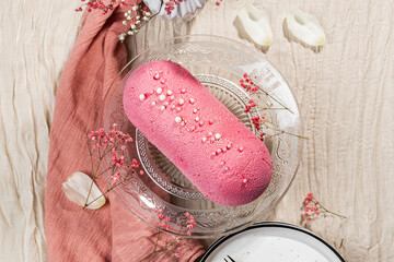 Mousse cake with pink velour and decorative sweet pearls on a glass cake plate. Low-calorie mousse...