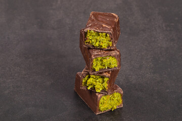 Dubai chocolate. Chocolate with crispy kataifi dough filling and emerald pistachio paste. Dark gray background