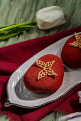 Mousse cakes with red velour, cakes with strawberry mousse and chocolate. Chocolate mousse. Red cakes on a white plate. Spring pastries. Cheesecake with chocolate and strawberries.