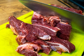 A display of freshly cut meat on a chopping board with a sharp knife nearby, ready to prepare