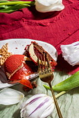 Mousse cakes with red velour, cakes with strawberry mousse and chocolate in a cut. Chocolate mousse. Red cakes on a white plate. Spring pastries. Cheesecake with chocolate and strawberries.