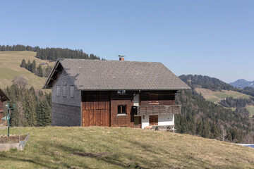 Scenic mountain house surrounded by green hills and trees at midday in a peaceful rural setting