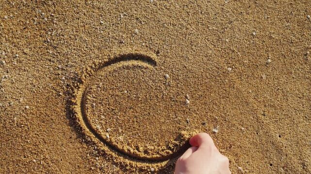Woman drawing a sign of peace in the sand on a sunny beach. High quality 4k footage