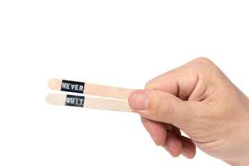 Hand holding wooden sticks with inscription never quit.