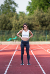 Obraz premium Athletic Young Caucasian Woman Posing Confidently on Outdoor Running Track for Fitness