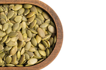 Pumpkin seeds in wooden bowl isolated on white background closeup.