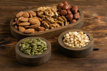 Assortment of nuts in bowls on wooden background. Healthy food.