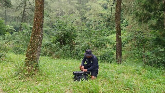 The process of setting up a shelter tent using a flysheet in the forest by a male adventurer. A traveler is setting up a flysheet for a bushcraft adventure in a pine forest area.