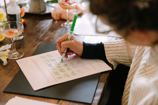 Creative calligraphy workshop in a cozy indoor setting with participants enjoying drinks and crafting letters
