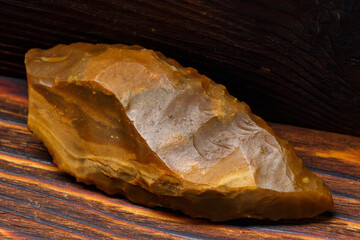 A flint spearhead with exquisite retouching on a wooden background, a relic from the Stone Age, found in central Russia.