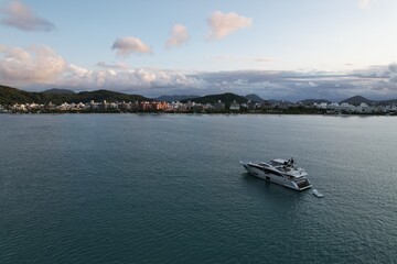 Luxury yacht anchored in calm waters near a coastal town at sunset