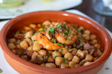 Garbanzas A vibrant dish of chickpeas sits invitingly in a warm,  pot, garnished with shrimps and...
