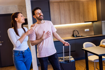Young couple comes into the apartment for their vacation. They carry the baggage with them. They are amazed by the apartment.