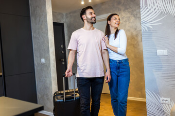 Young couple comes into the apartment for their vacation. They carry the baggage with them.