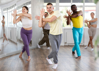 Positive guy engaged in active dance together with other attendees of dancing courses